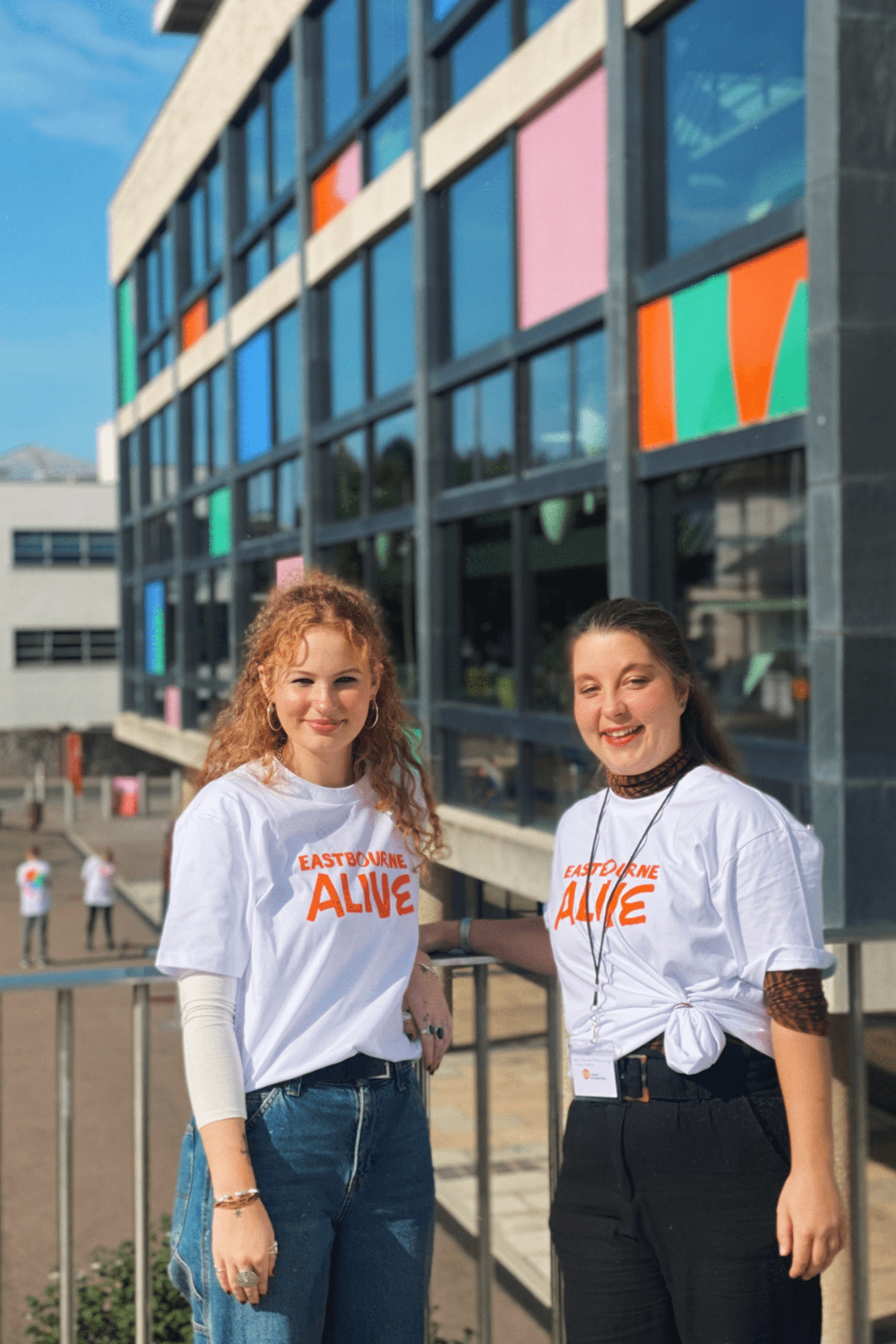 Two volunteers standing in front of the Congress Theatre, wearing Eastbourne Alive T-shirts