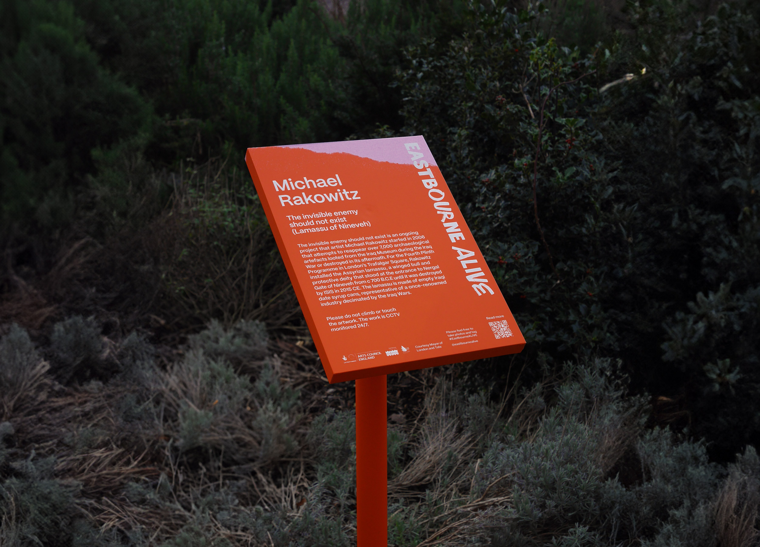 Bright orange Eastbourne Alive interpretation board with matching orange pole in gardens near Towner Eastbourne